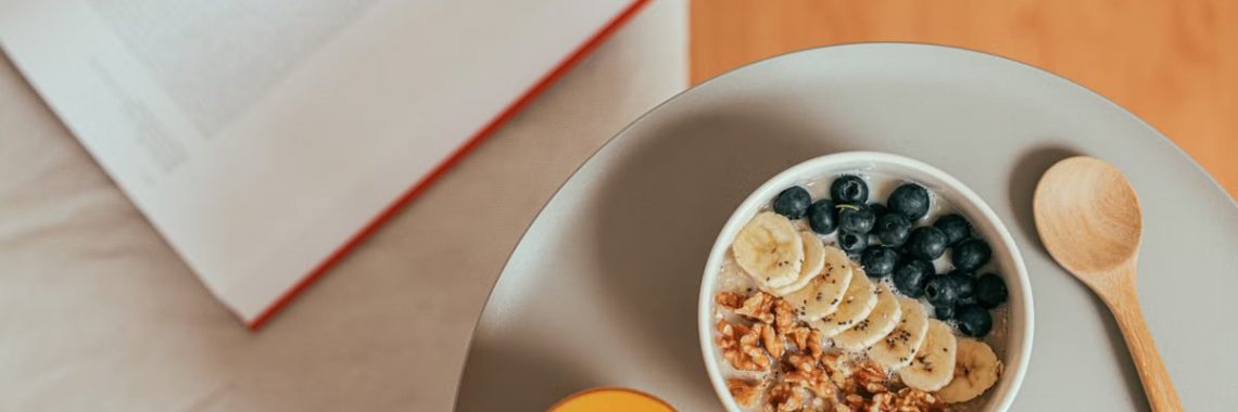 Top view of healthy breakfast with oatmeal, fresh fruit, and orange juice on a tray.